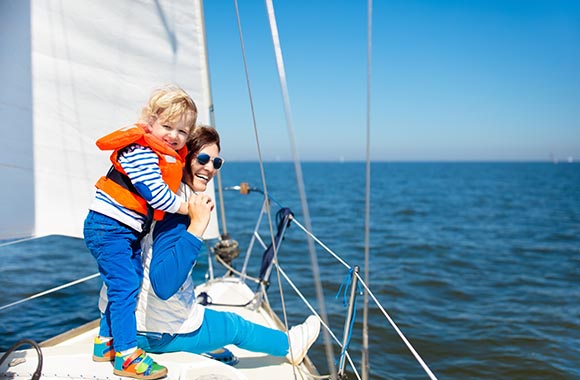 Uitrusting voor het zeilen – Moeder en zoon op het water met reddingsvest en zonnebril. Uitrusting voor het zeilen – Moeder en zoon op het water met reddingsvest en zonnebril.