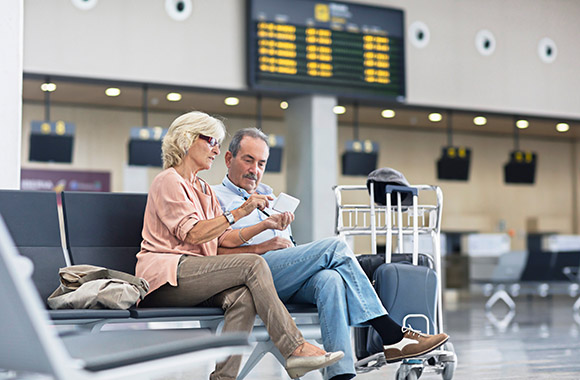 Un couple dans un aéroport vérifie les modalités de leur vol sur leur smartphone. Un couple dans un aéroport vérifie les modalités de leur vol sur leur smartphone.