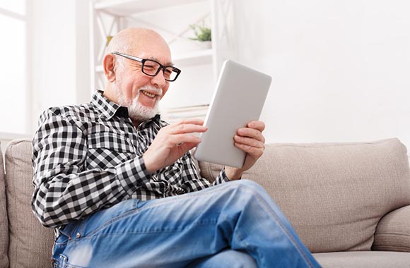Starszy mężczyzna używa aplikacji Messenger na tablecie. Starszy mężczyzna używa aplikacji Messenger na tablecie.
