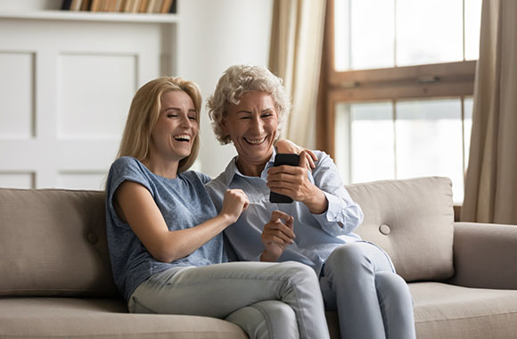 Smartphone voor senioren instellen – Moeder en dochter kijken samen op een mobiele telefoon. Smartphone voor senioren instellen – Moeder en dochter kijken samen op een mobiele telefoon.
