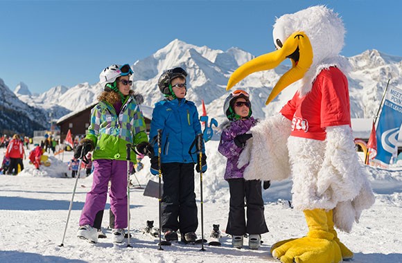 Kinder auf Ski neben Maskottchen. Kinder auf Ski neben Maskottchen.