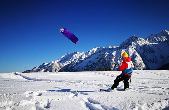 Sportivo sullo snowboard che pratica snowkite.