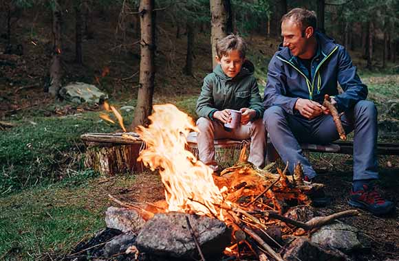 Vater und Sohn machen ein Lagerfeuer an einer Feuerstelle. Vater und Sohn machen ein Lagerfeuer an einer Feuerstelle.