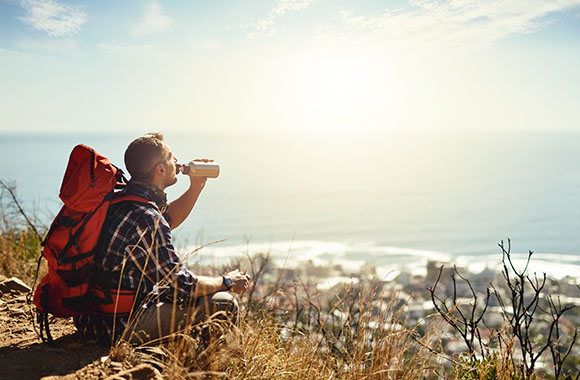 Hiker takes a break on the way and drinks a sip of water.