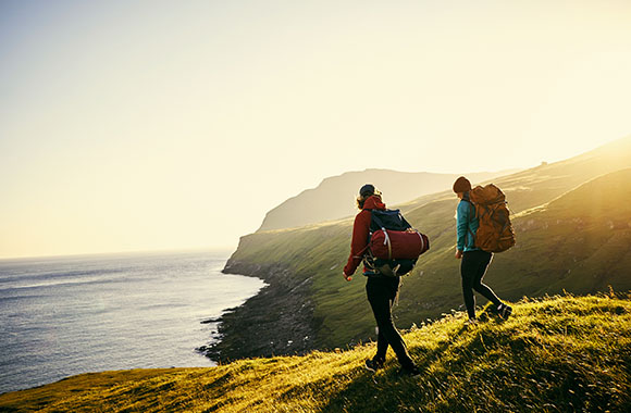 Twee wandelaars wandelen over een berg met een uitzicht over de zee.