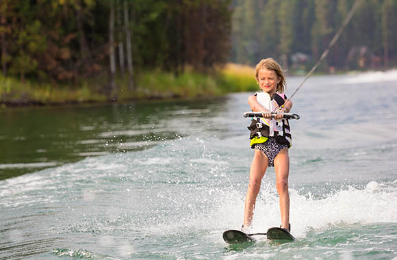 Narty wodne dla dzieci – dziewczynka pływa na nartach wodnych.
