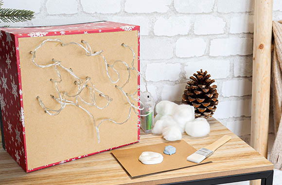 Attaching the LED light chain for the craft idea Christmas landscape in the box.