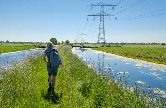Trekvogelpad wandelen – Vrouw loopt door een drassig weiland. Trekvogelpad wandelen – Vrouw loopt door een drassig weiland.