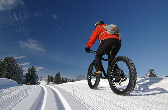 Un homme fait du Fat Bike en hiver à la montagne.