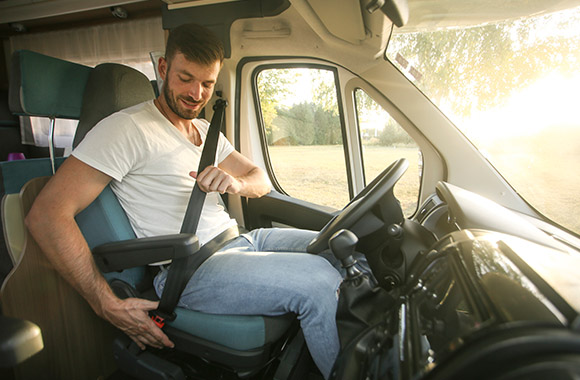 Veiligheid in de camper - de bestuurder maakt zijn riem vast in de camper. Veiligheid in de camper - de bestuurder maakt zijn riem vast in de camper.