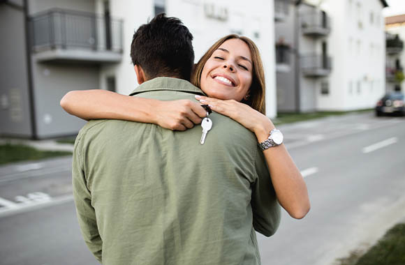 Une femme enlace son compagnon après la remise des clés de leur appartement.