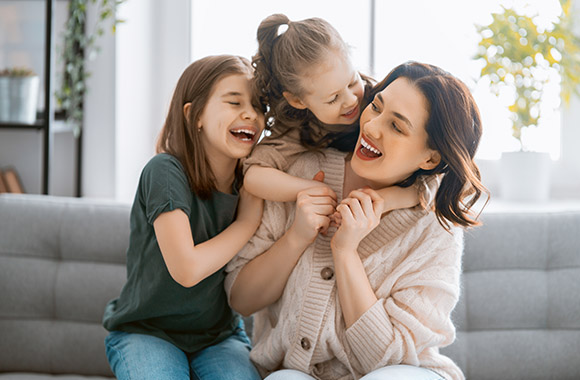 Beschäftigung für zuhause – Mutter und Töchter spielen auf dem Sofa.