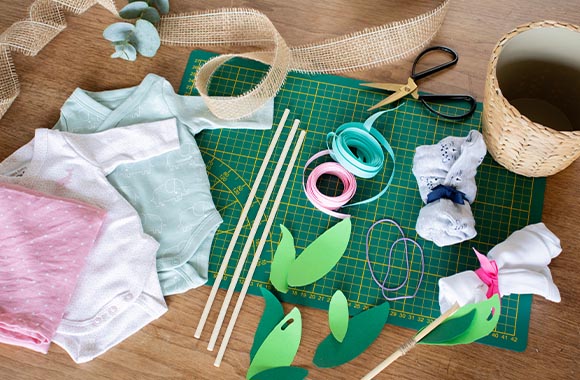 Tous les matériaux nécessaires pour réaliser un bouquet fait maison à partir de bodies pour bébé. Tous les matériaux nécessaires pour réaliser un bouquet fait maison à partir de bodies pour bébé.