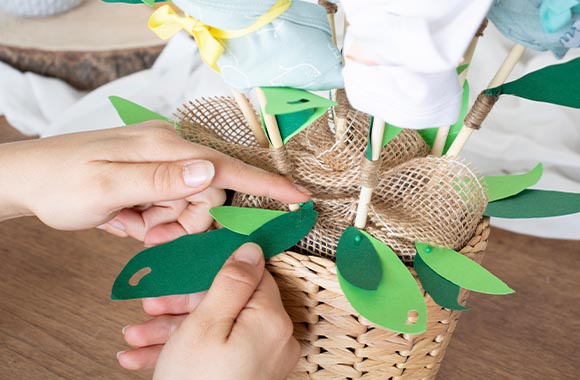 Bouquet de bodies pour bébé dans un pot décoré de feuilles et de ruban en tissu. Bouquet de bodies pour bébé dans un pot décoré de feuilles et de ruban en tissu.
