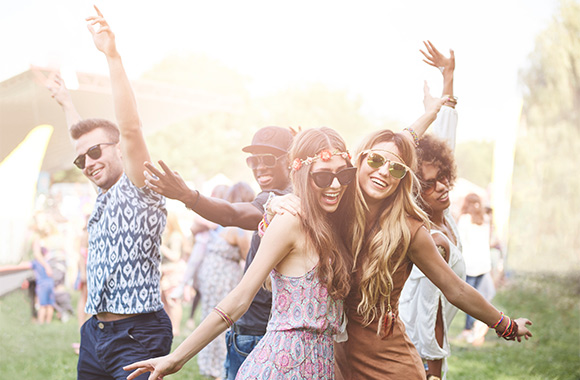 Friends wearing boho outfits and dancing at a Festival.