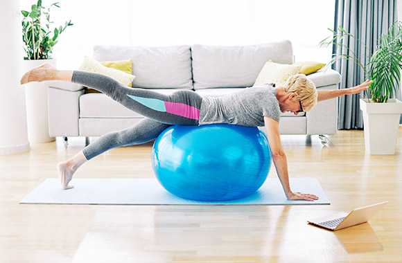 Woman training at home using a gym ball.