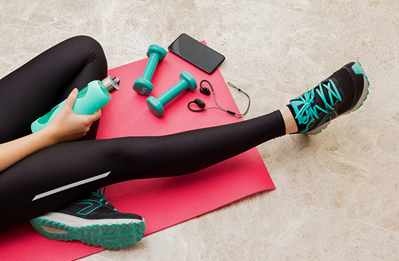 Close-up of fitness accessories: yoga mat, small dumbbells, sports clothing.