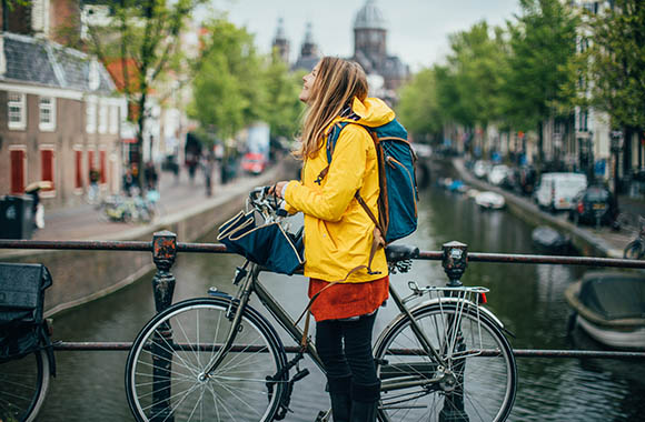 Fahrrad fahren bei Regen: Frau schützt sich mit einer Regenjacke vor Nässe beim Radfahren.