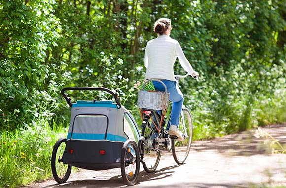 Baby mit Fahrrad mitnehmen: Frau unternimmt eine Radtour mit Fahrradanhänger. Baby mit Fahrrad mitnehmen: Frau unternimmt eine Radtour mit Fahrradanhänger.