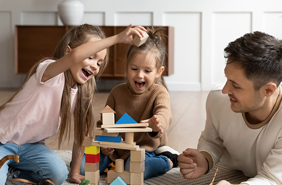 Pädagogisch wertvolles Spielzeug – Familie spielt mit Bauklötzen.