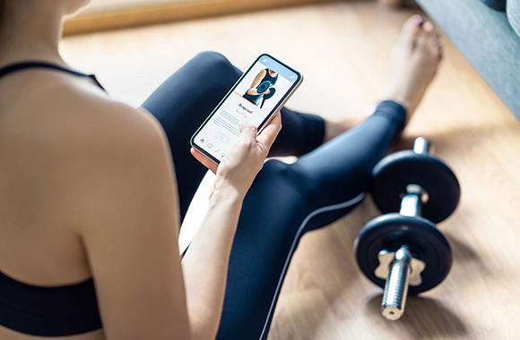 Online fitness course: woman viewing a video workout in a fitness app.