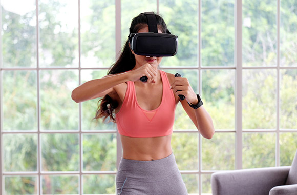 Young woman wearing VR-goggles for training with a fitness game.