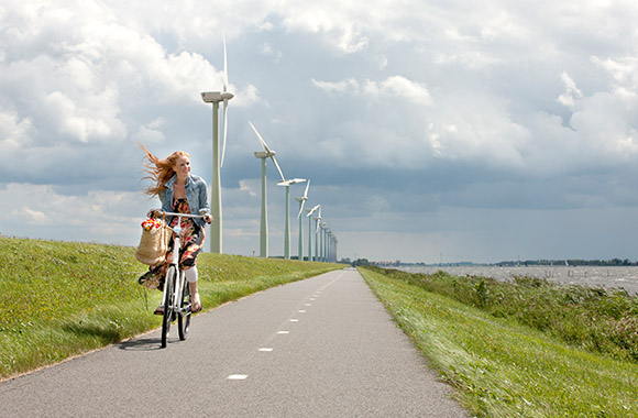 De Windmolenroute – Fietser met windmolens op de achtergrond. De Windmolenroute – Fietser met windmolens op de achtergrond.