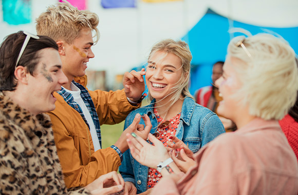 Festival outfits: a group of friends applying glitter to their faces. Festival outfits: a group of friends applying glitter to their faces.