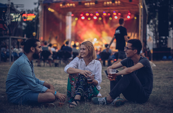 A group of friends sitting near the stage at a festival. A group of friends sitting near the stage at a festival.