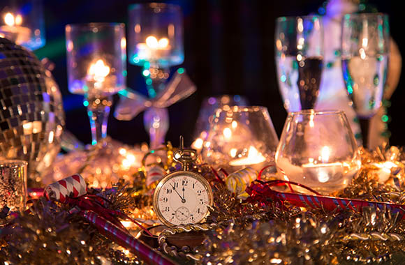 Shiny golden New Year’s Eve decorations and champagne glasses on a table.