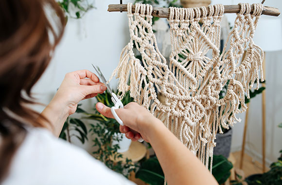 Macramé for beginners: Woman knotting a macramé wall hanging. Macramé for beginners: Woman knotting a macramé wall hanging.