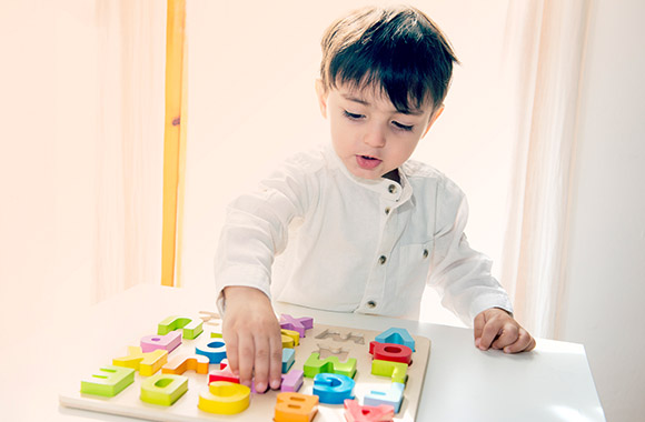Alvast het lezen stimuleren: jongen speelt met houten letters. Alvast het lezen stimuleren: jongen speelt met houten letters.