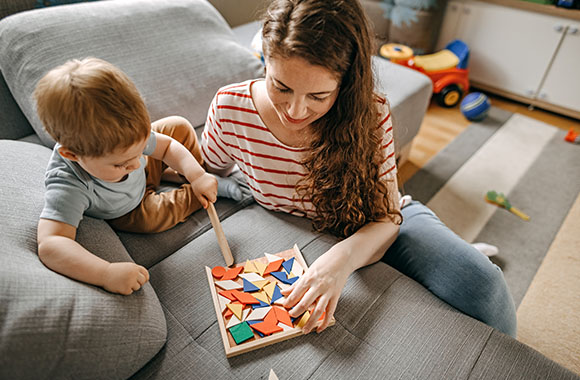 Duurzaam speelgoed - Moeder en zoon spelen met een houten puzzel. Duurzaam speelgoed - Moeder en zoon spelen met een houten puzzel.