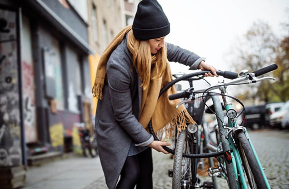 Una ragazza mette il lucchetto alla sua bici.