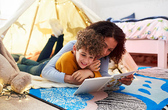 Invogliare alla lettura: madre e figlio leggono insieme in un’accogliente cameretta.