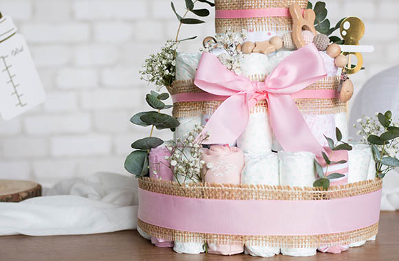Un gâteau de couches décoré avec des nuances de rose pour une fille.