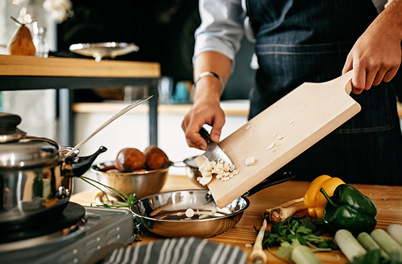 Learning to cook: Hobby cook puts cut ingredients into a pan.