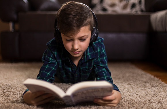 Jongen leest een boek met koptelefoon. Jongen leest een boek met koptelefoon.