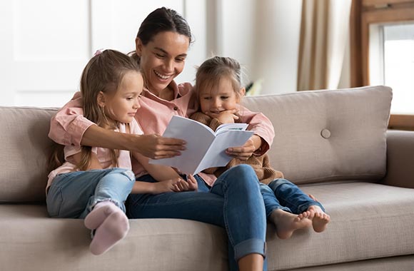Leren lezen door voor te lezen: moeder leest haar dochters voor.