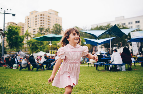 Family-friendly festival: little girl running across a field at a family-friendly festival.