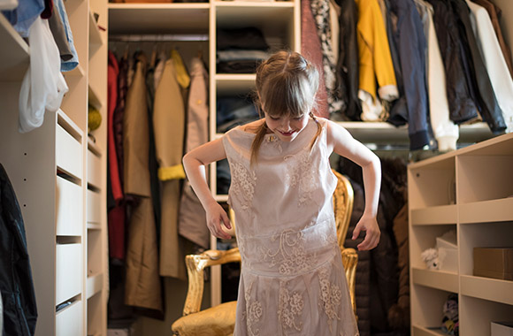 Kinderspelletjes – een meisje trekt een jurk van haar mama aan.