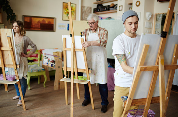 Deelnemers aan een kunstcursus concentreren zich op hun schildersezel.