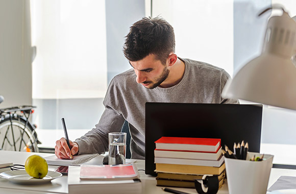 Professionele bijscholing: jonge man studeert thuis aan zijn bureau. Professionele bijscholing: jonge man studeert thuis aan zijn bureau.