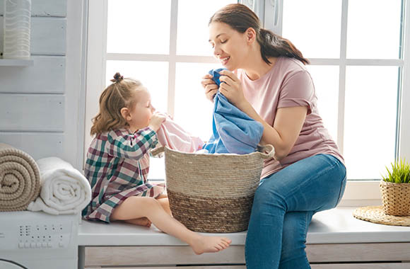 Lavatrice programma eco: una mamma e una bambina annusano il bucato pulito. Lavatrice programma eco: una mamma e una bambina annusano il bucato pulito.