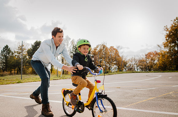 Bicicletas seguras para niños: un padre enseña a montar en bici a su hijo. Bicicletas seguras para niños: un padre enseña a montar en bici a su hijo.