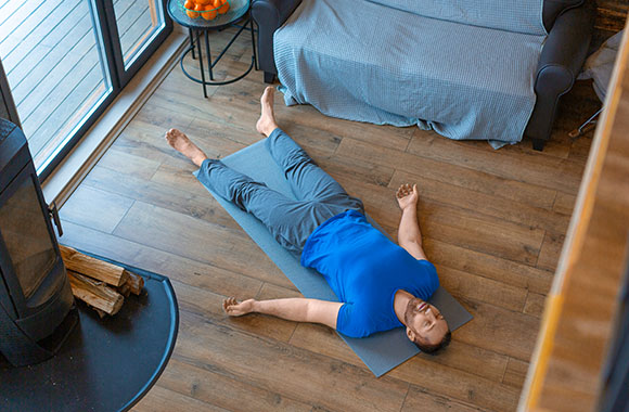 Yoga Pose Savasana – man lying on a yoga mat.
