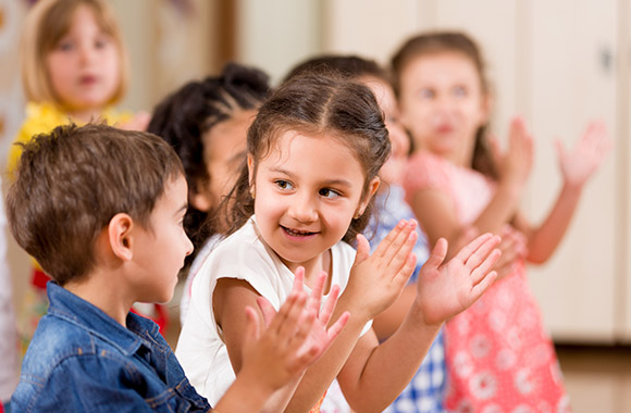 Des enfants en maternelle se tapent les mains en jouant à la division des syllabes.