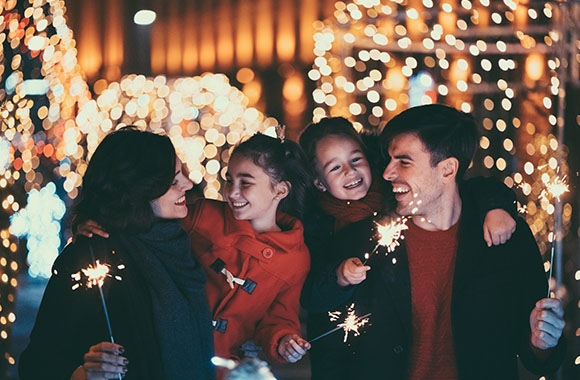 New Year’s Eve with children: Family lights sparklers together.