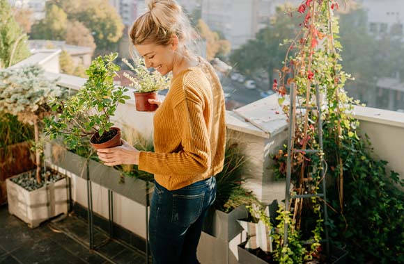 Balcon-jardin : une femme amène ses plantes sur le balcon pour le printemps. Balcon-jardin : une femme amène ses plantes sur le balcon pour le printemps.