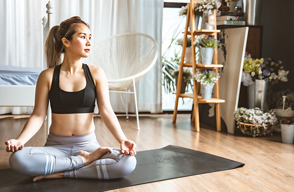 Yoga at home: Woman sitting down cross-legged for her yoga exercises.